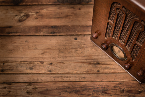 Color image, slightly desaturated, of an old tube radio sitting on a wood table. Includes room for your text.