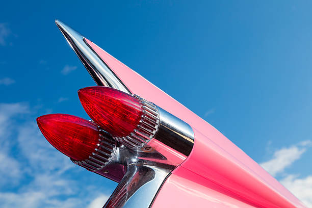 Tail Fin of Classic Car, 1959 Pink Cadillac de Ville Geiselwind, Germany - June 20, 2015: Tail fin of  classic car, 1959 pink Cadillac de Ville  at a vintage American car meeting, low angle view against blue sky. 1959 photos stock pictures, royalty-free photos & images