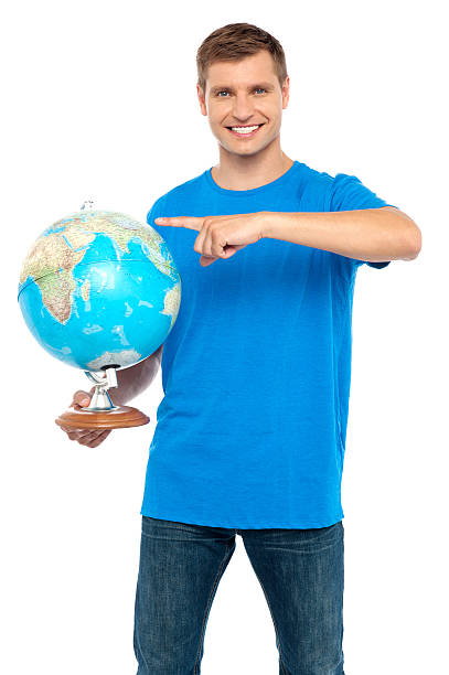 Casual cool guy pointing at rotating globe Casual cool guy pointing at rotating globe isolated over white background finger spinning globe stock pictures, royalty-free photos & images