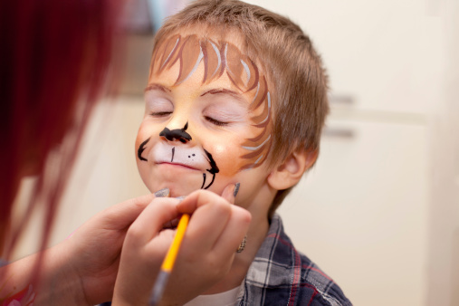 Poco niño con pintura de la cara de un león photo