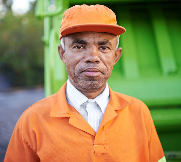 Keeping streets clean is his goal! Cropped portrait of a garbage collection worker standing by a garbage truck street sweeper stock pictures, royalty-free photos & images