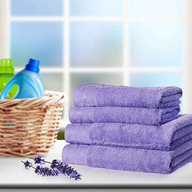 Pile of towels and liquid laundry detergent on the table.