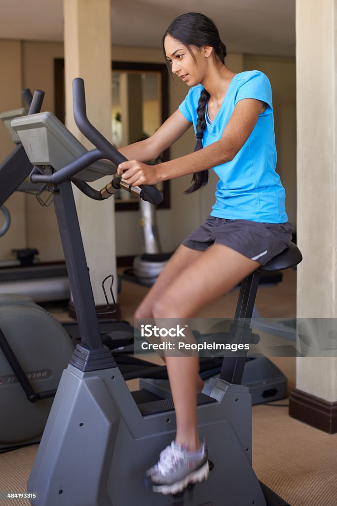 Full body workout! Shot of a young ethnic woman working out in the gym on a stationary bikehttp://195.154.178.81/DATA/i_collage/pi/shoots/783172.jpg 20-29 Years Stock Photo