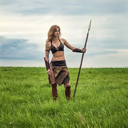 Beautiful red-haired girl in the image of ancient warriors on the background of nature.