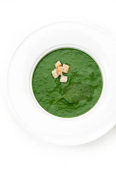 Traditional spinach cream soup with croutons in the white plate. top view