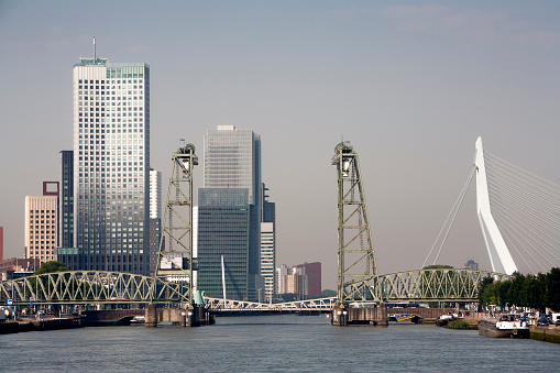 Cityscape  of the south bank of the Meuse river in Rotterdam, opposite the center of town. De Hef, the old green steel rail bridge is a monument and not in use anymore.  The Erasmusbridge is on the right side