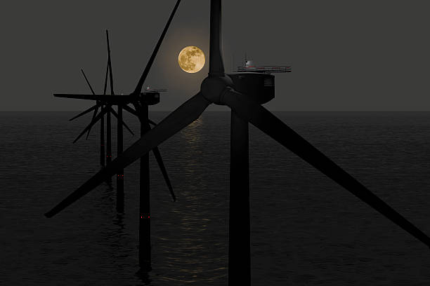 Wind Turbines at Night Offshore wind turbines in a row with moonlight to illustrate that they are working 24h. floating electric generator stock pictures, royalty-free photos & images