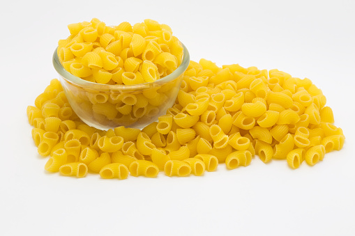 Glass bowl of Raw macaroni pasta on white background