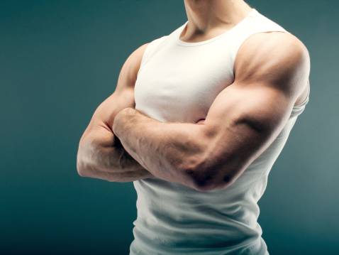 Male person with strong arms in white shirt over green background.