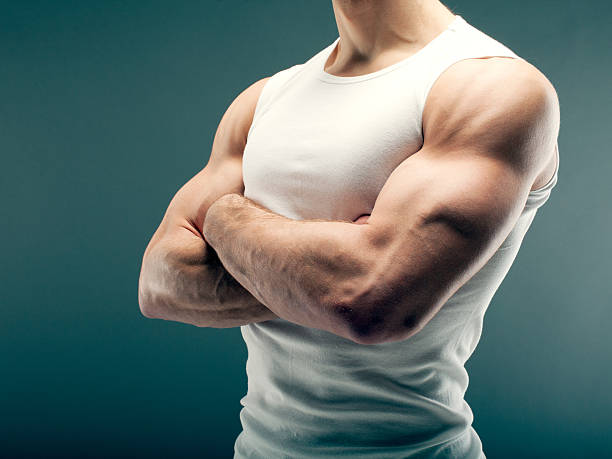 Strong guy with crossed arms Male person with strong arms in white shirt over green background. bicep stock pictures, royalty-free photos & images