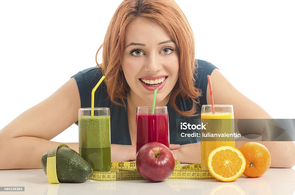 Happy woman holding two different organic smoothie Happy woman holding two different organic smoothie. Cheerful young woman eating healthy fruits and drinking orange juice and green smoothie Adult Stock Photo