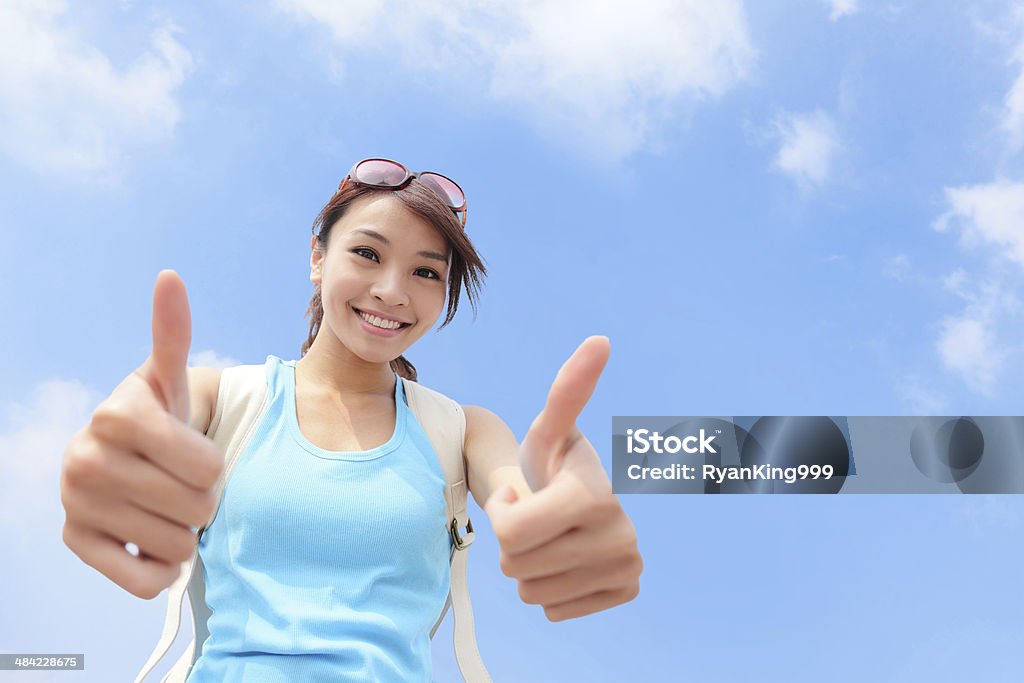 smiling woman tourist showing thumbs up Cheerful smiling woman tourist showing thumbs up success sign with sky background OK Sign Stock Photo