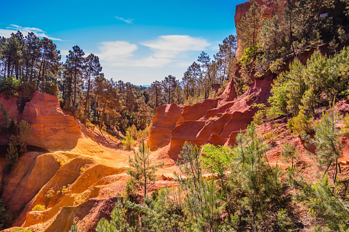 Scenic pit mining ocher - natural dyes. Roussillon, Provence Red VillageMulti-colored outcrops - from yellow to red-orange. Green trees create beautiful contrast from ochre. Roussillon, Red village of Provence