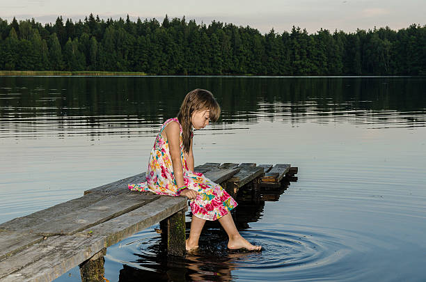 The girl sat on the wooden bridge at the lake.
