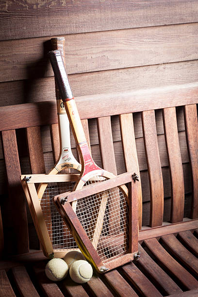 Wilson Tennis Racquets Gualala, California, USA - August 13, 2015: Vintage Wilson Tennis Racquets with ball on bench. Wilson is the world's leading manufacturer of ball sports equipment. It is located in Chicago USA with over 1600 employees worldwide. The Chris Evert wood tennis racquet is the model shown from the 1970s. She is a former number one professional tennis player with 18 Grand Slam singles titles. wimbledon seats stock pictures, royalty-free photos & images