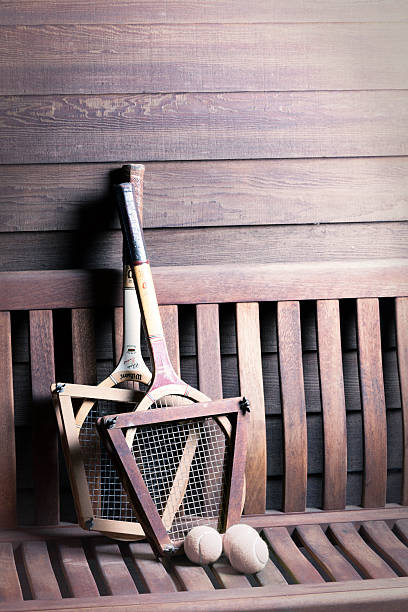 Wilson Tennis Racquets Gualala, California, USA - August 13, 2015: Vintage Wilson Tennis Racquets with ball on bench. Wilson is the world's leading manufacturer of ball sports equipment. It is located in Chicago USA with over 1600 employees worldwide. The Chris Evert wood tennis racquet is the model shown from the 1970s. She is a former number one professional tennis player with 18 Grand Slam singles titles. wimbledon seats stock pictures, royalty-free photos & images