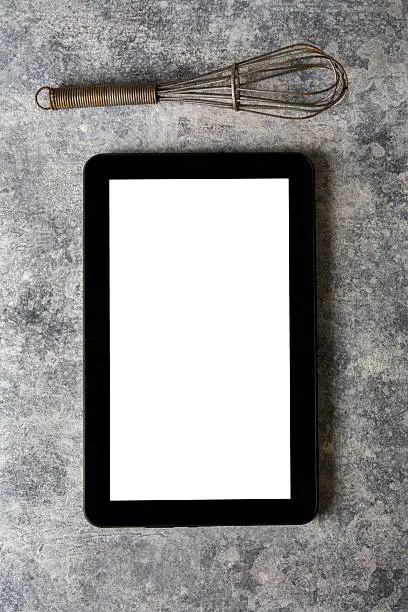 Photo of Digital tablet, with whisk and antique silverware, on grunge bac