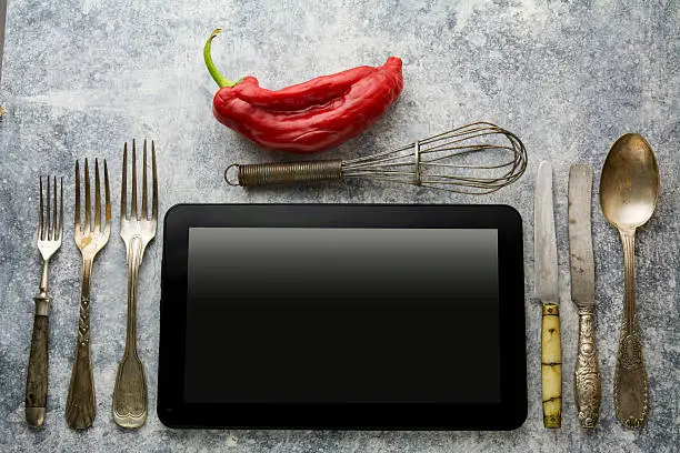 Photo of Digital tablet, with whisk and antique silverware, on grunge bac