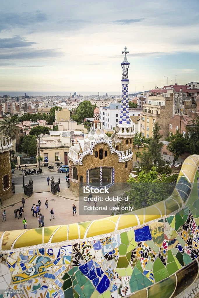 Ceramic bench and entrance pavilion of park Guell Barcelona, Spain - May 31, 2013: View of ceramic mosaic bench of park Guell, with people walking around the entrance pavilion on the background. Designed by Antonio Gaudi. Antoni Gaudí Stock Photo