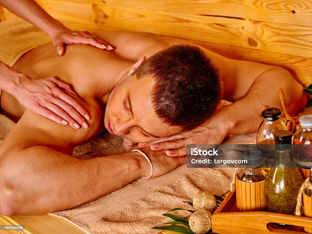 Woman getting bamboo massage Man getting massage in bamboo spa. Female therapist. 2015 Stock Photo