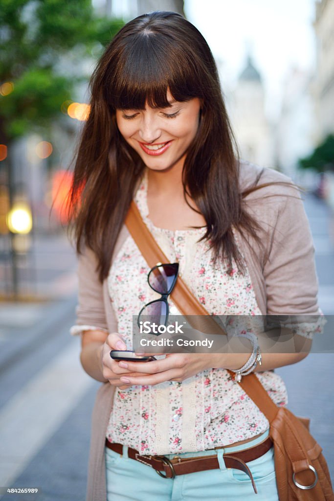 Young woman in the city Young beautiful women texting on phone and smiling in the streets of the city. 20-29 Years Stock Photo
