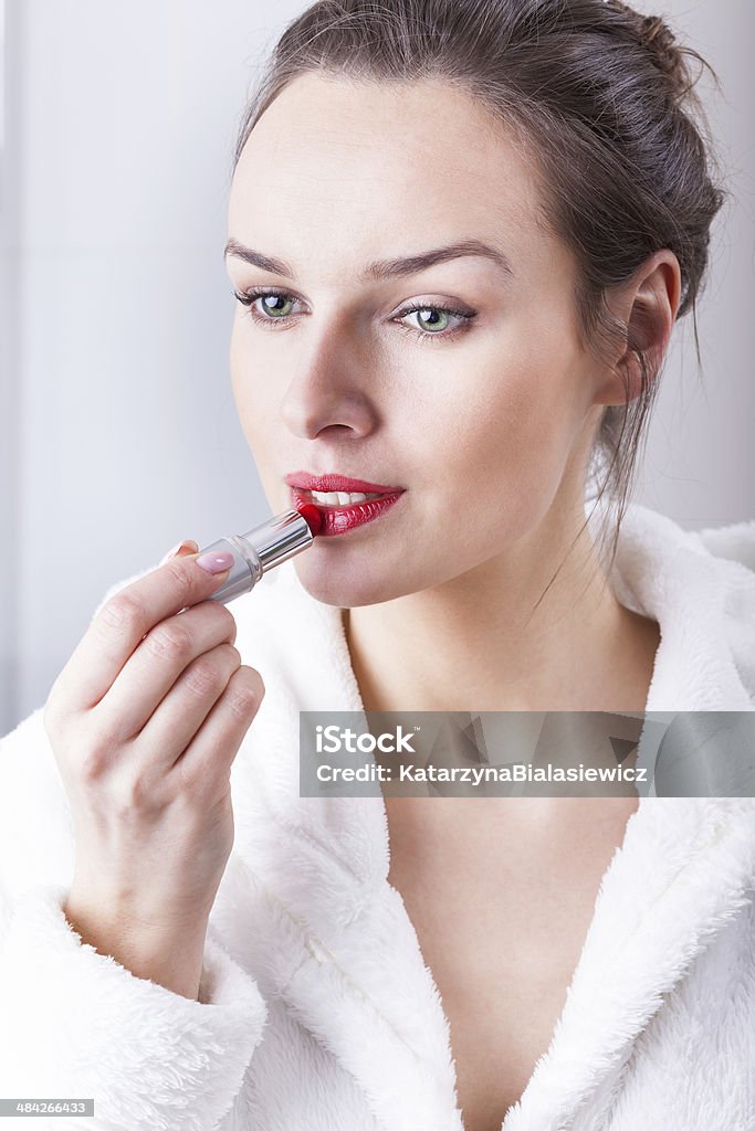 Young woman applying lipstick Young woman before a date applying red lipstick Adult Stock Photo