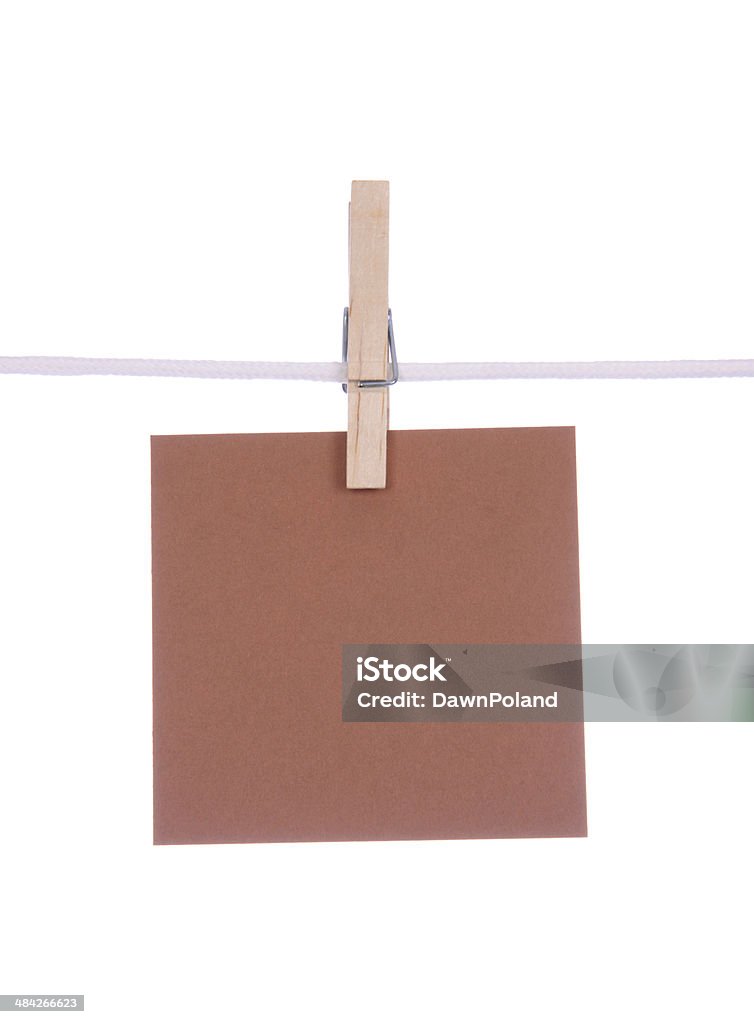 Blank Paper A blank piece of brown paper hanging from a clothesline on a white background. Adhesive Note Stock Photo