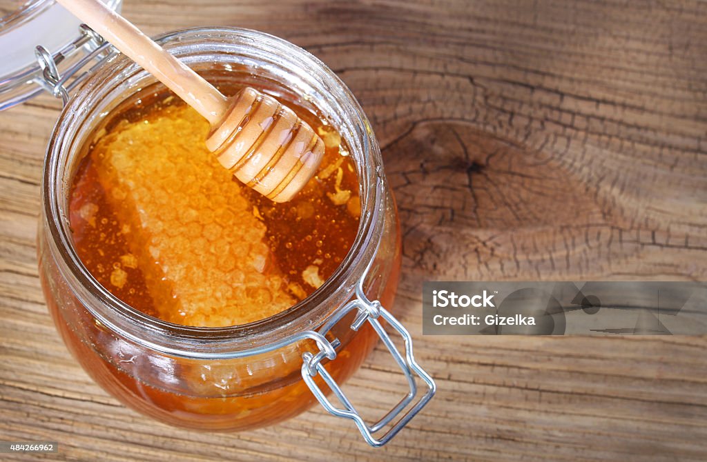 Jar of honey with honeycomb and dipper Jar of honey with honeycomb and dipper on wooden background 2015 Stock Photo