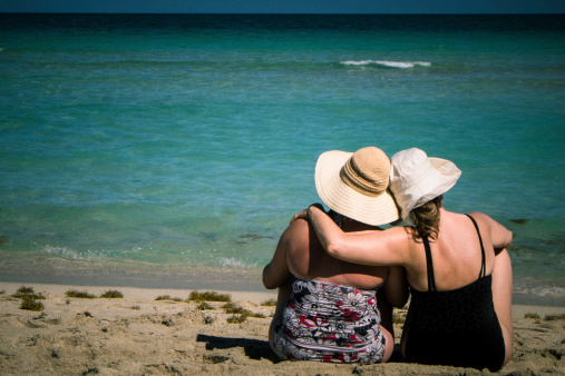 Two mature lesbian women posing embracing looking at the horizon over the water