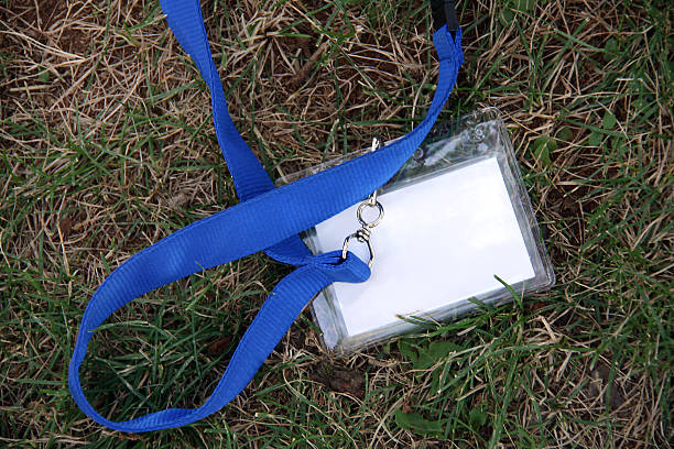 White name tag, blue lanyard, in the grass.  Copy space. stock photo