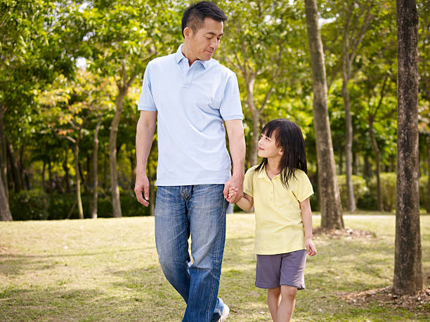 asian father and daughter takes a walk in park asian father and elementary-age daughter enjoying a walk in nature. child japanese culture japan asian ethnicity stock pictures, royalty-free photos & images