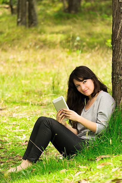 istock Happy young woman with digital tablet sitting on grass in 484289155