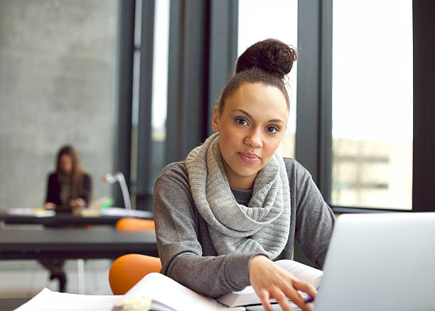istock Young woman studying in library using laptop 484289403