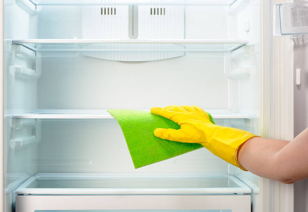 istock Woman's hand in yellow glove cleaning refrigerator with green rag 484299844