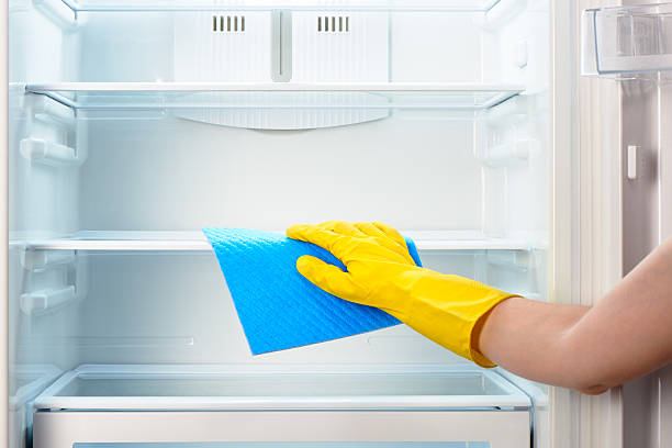 istock Woman's hand in yellow glove cleaning refrigerator with blue rag 484299846