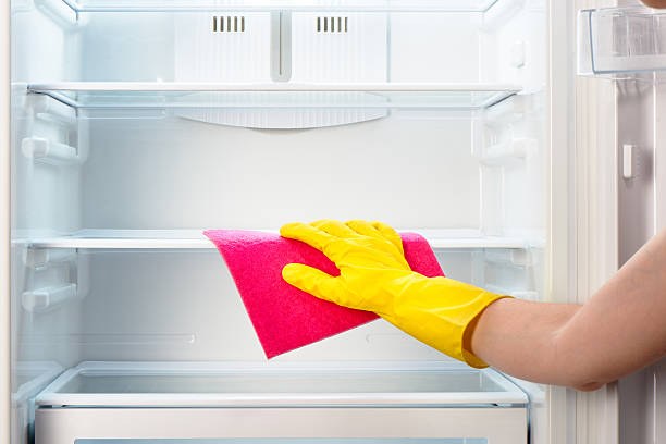 istock Woman's hand in yellow glove cleaning refrigerator with pink rag 484299850