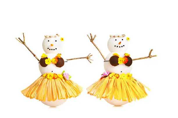Snowman vacationing in tropical Hawaii, dancing in Hula costume on white background. Photographed in studio, isolated in white background in horizontal format with copy space. Winter snowbirds concept for travelers from cold weather region vacationing in tropical locations.