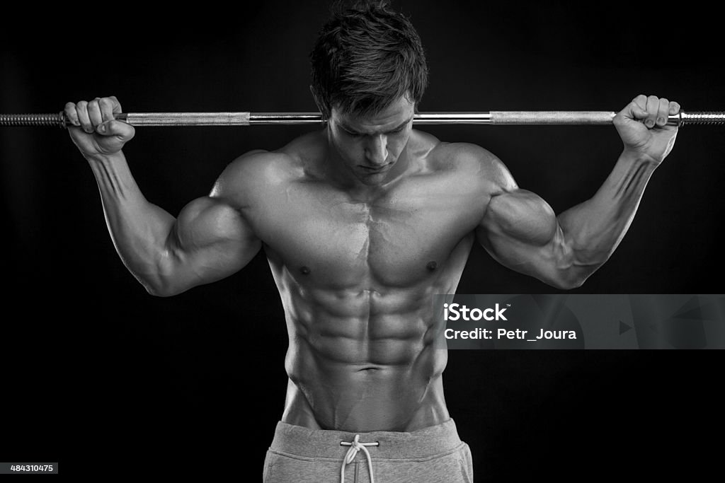 Muscoloso bodybuilder guy facendo esercizi con manubri - Foto stock royalty-free di Abbronzatura