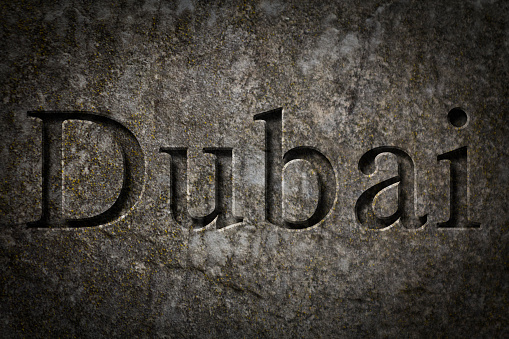 Engraving spelling the city Dubai on textured old surface