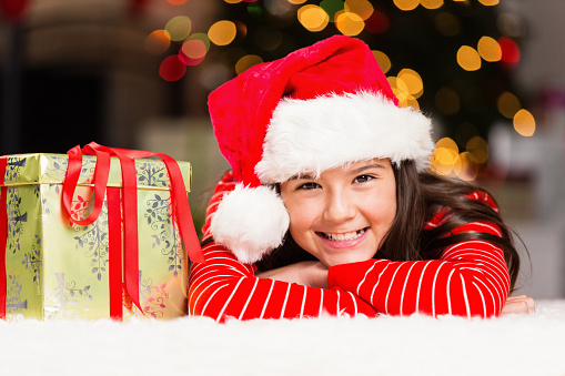 Adorable preteen girl waiting to open gift on Christmas morning