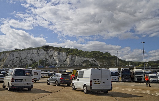 Dover, UK - July 27, 2015: vehicles at Dover ferry port UK, there is a traffic control officer directing them to the exit.
