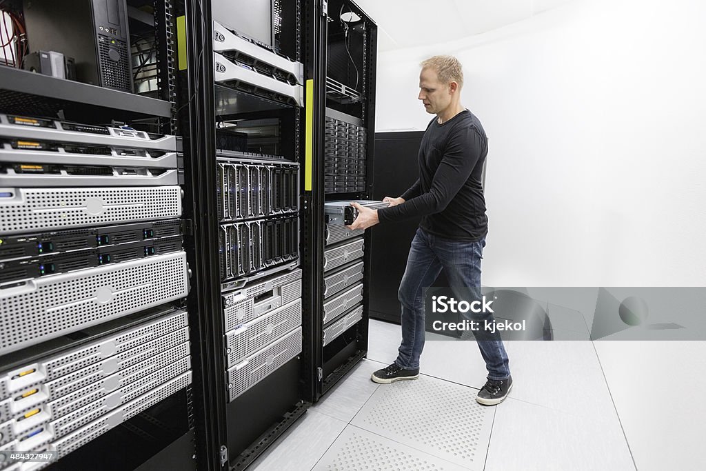 It professional install rack server in datacenter It engineer or consultant installing rack server. Shot in data center. Adult Stock Photo