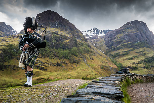 bagpiper tradicional en la región montañosa de escocia por glencoe - falda escocesa fotografías e imágenes de stock
