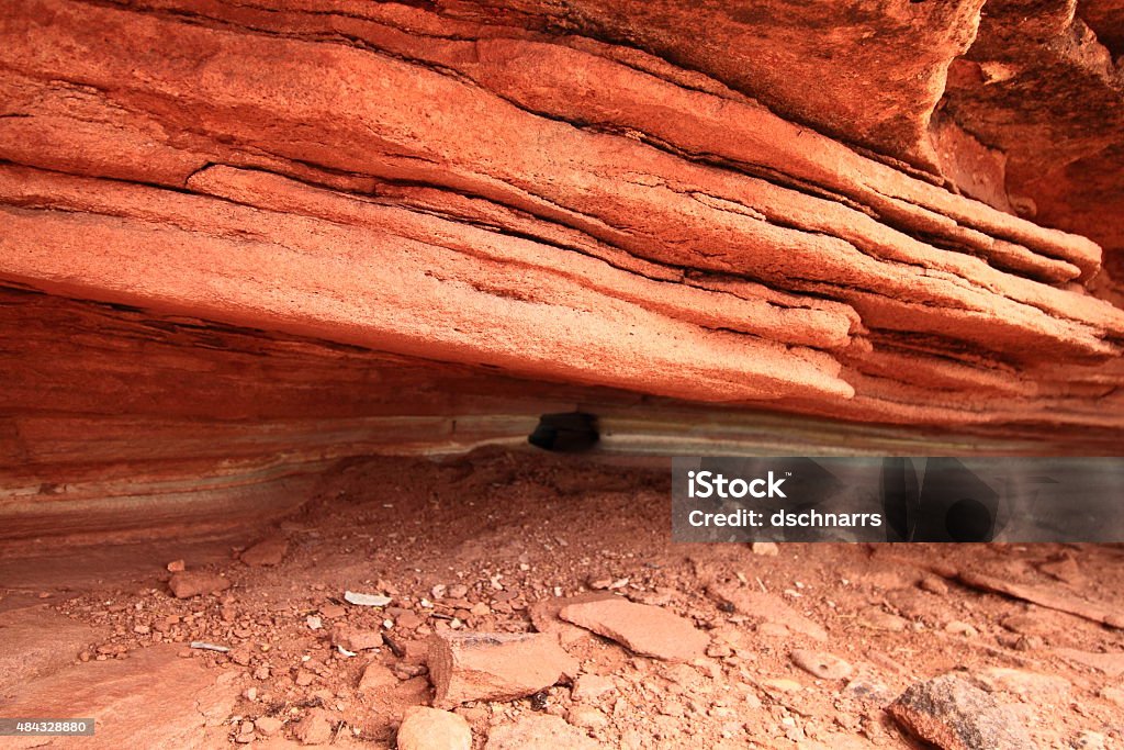 Striated sedimentary rock This is a close up shot of eroded rock in Colorado. There is sand on the ground, and the bright red rock's striations and beautiful color variation can be seen as it moves across the background of the photo. This was taken at the Colorado National Monument, where severe erosion has washed away much of the landscape, but leaves behind beautiful cliff walls and rock inlets like this one. Abstract Stock Photo