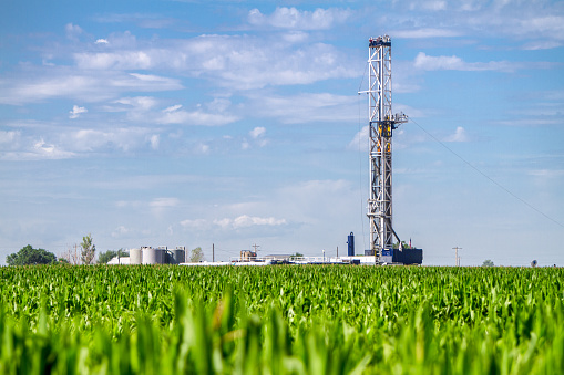 Close shot of a drilling Fracking Rig in a corn field.  Fracking Rig is performing a fracking operation to liberate trapped crude oil and natural gas into the pipeline to a refinery.