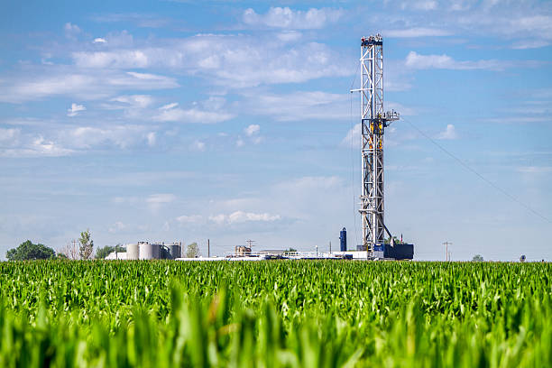 Corn Field Drilling Fracking Rig Close shot of a drilling Fracking Rig in a corn field.  Fracking Rig is performing a fracking operation to liberate trapped crude oil and natural gas into the pipeline to a refinery. shale stock pictures, royalty-free photos & images