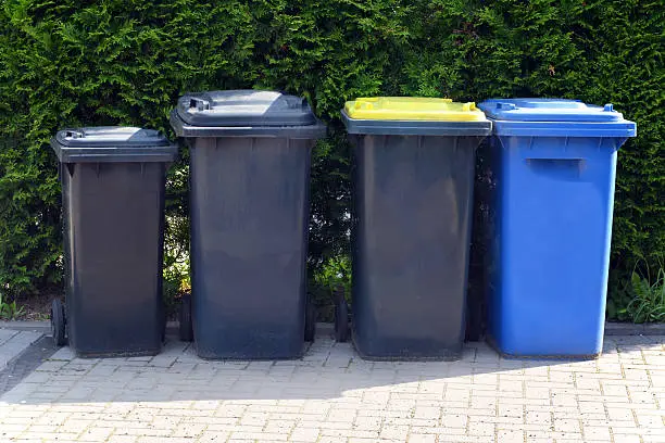 overfilled trash of large wheelie bins for rubbish, recycling and garden waste