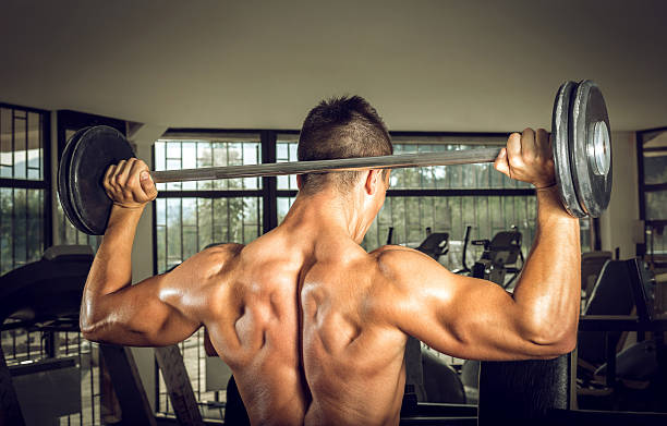 istock Young man lifting barbell. View from behind. 484336360