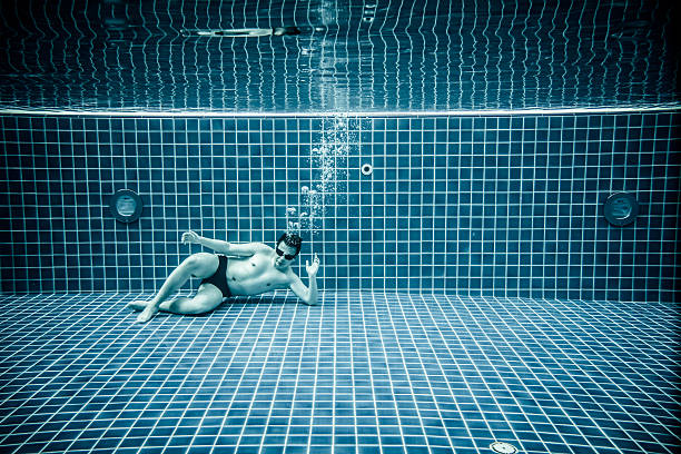 Man lies under water in a swimming pool