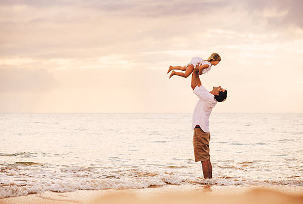 Father and Daughter Playing Together at the Beach at Sunset stock photo